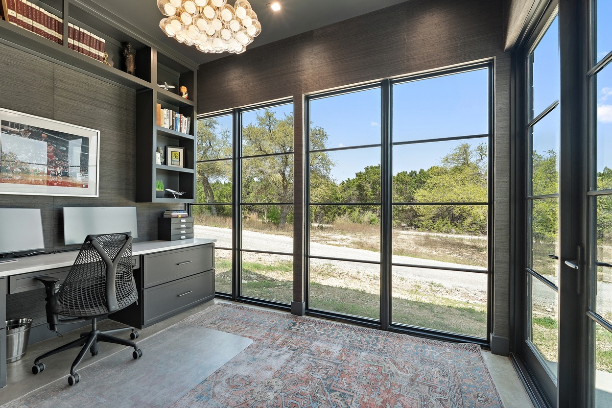 Corner office space inside a detached casita by J. Angelo Design Build in Austin, TX with expansive windows and built-in shelves